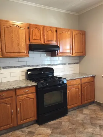 a kitchen with granite countertop a stove top oven sink cabinetry and granite counter top