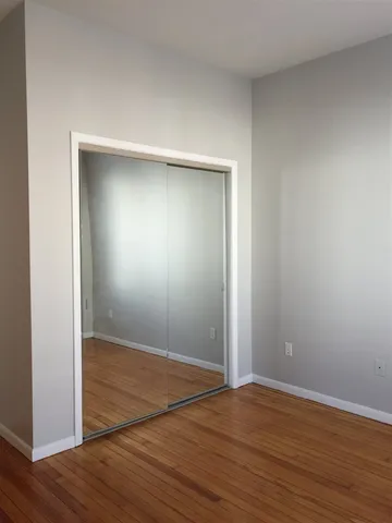 an empty room with wooden floor and entrance