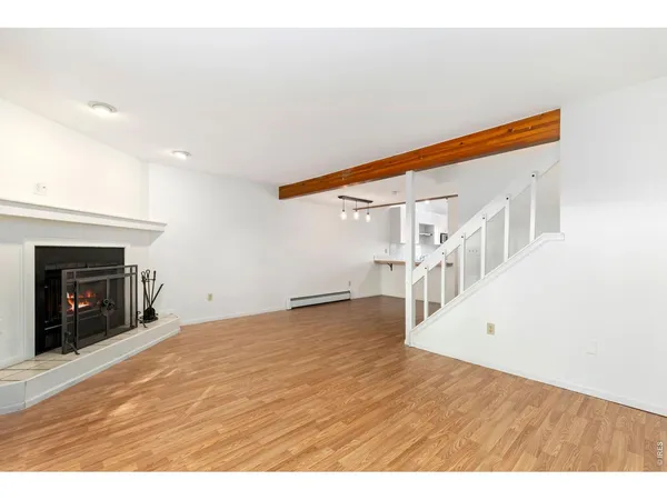 a view of an empty room with wooden floor and a fireplace