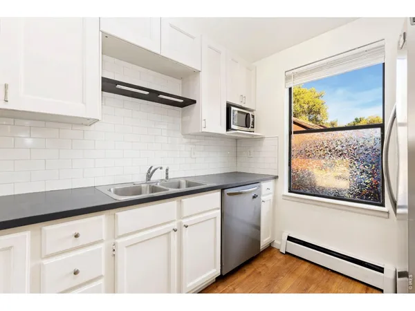 a kitchen with stainless steel appliances granite countertop white cabinets a stove and a refrigerator
