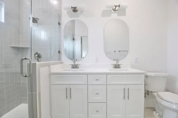 a bathroom with a double vanity sink toilet and a mirror
