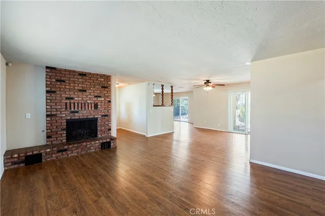 an empty room with wooden floor fireplace and windows