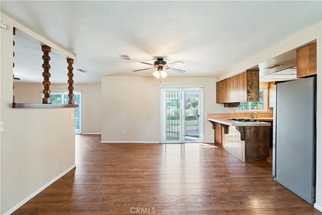 a view of a kitchen with furniture a ceiling fan and wooden floor