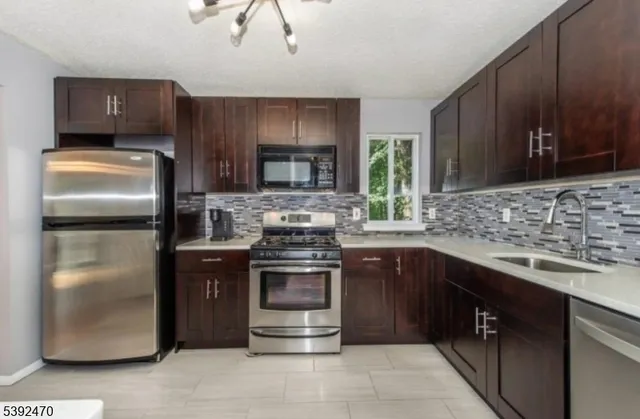a kitchen with stainless steel appliances granite countertop a stove a refrigerator and a sink