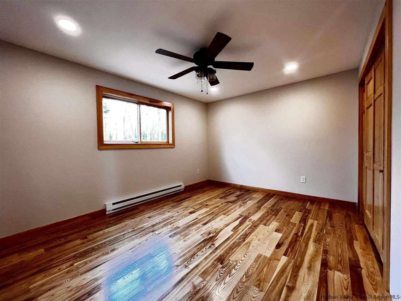 133 Rockefeller Lk Road Cairo, NY 12413 - Photo 24 of 35 an empty room with wooden floor fan and windows