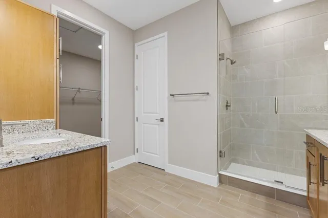 a bathroom with a granite countertop sink a mirror and shower