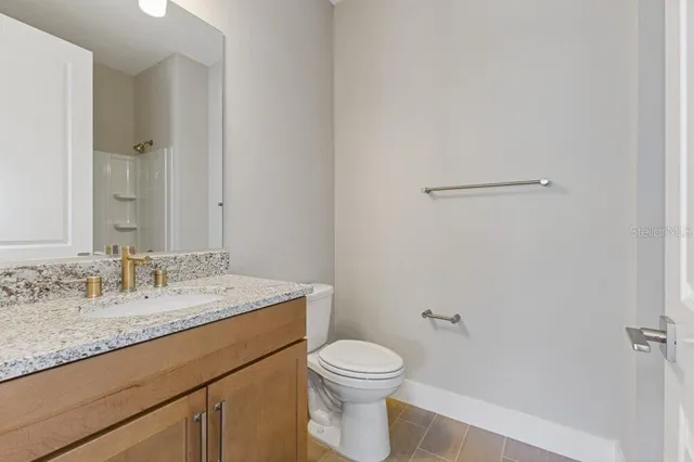 a bathroom with a granite countertop sink a toilet and a mirror
