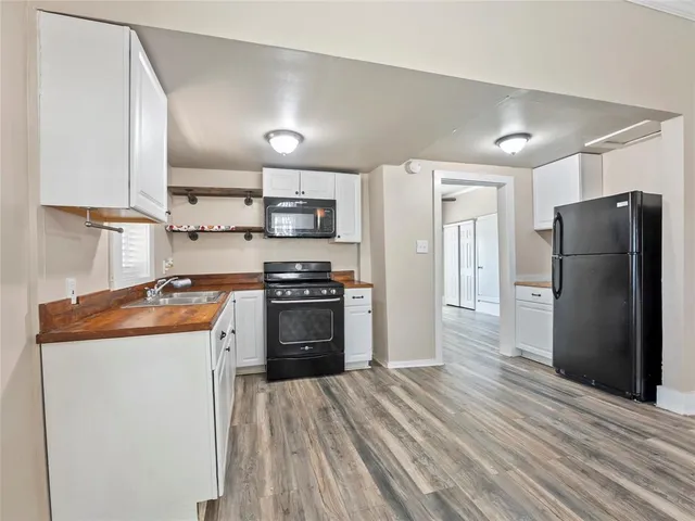 a kitchen with stainless steel appliances granite countertop a refrigerator a stove and a sink with wooden floor