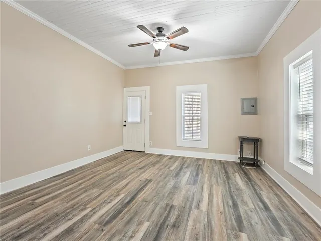 an empty room with windows and ceiling fan