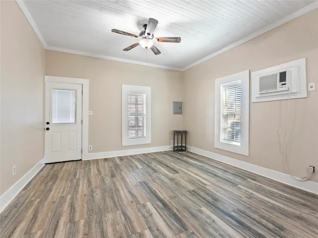 a view of an empty room with a window and wooden floor