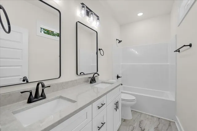 a bathroom with a granite countertop sink a toilet and a bathtub