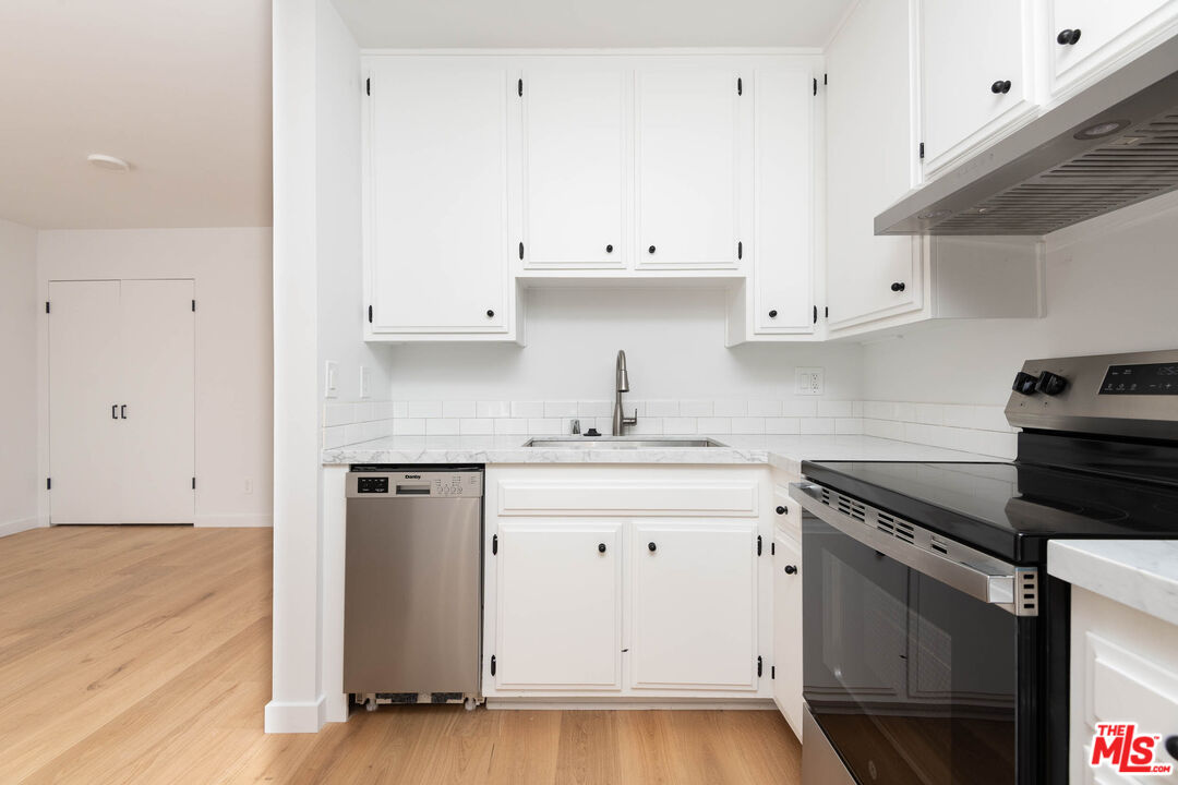 5935 Chula Vista Way, Unit 103 Los Angeles, CA 90068 - Photo 2 of 12 a kitchen with granite countertop white cabinets and black appliances
