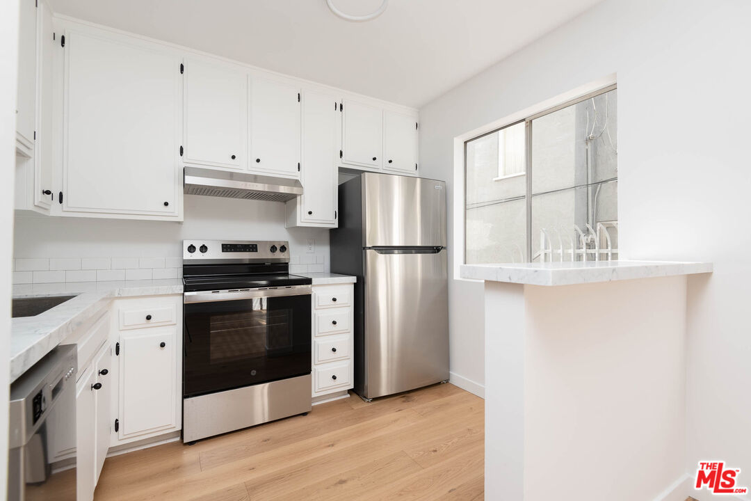 5935 Chula Vista Way, Unit 103 Los Angeles, CA 90068 - Photo 3 of 12 a kitchen with stainless steel appliances a refrigerator sink and cabinets