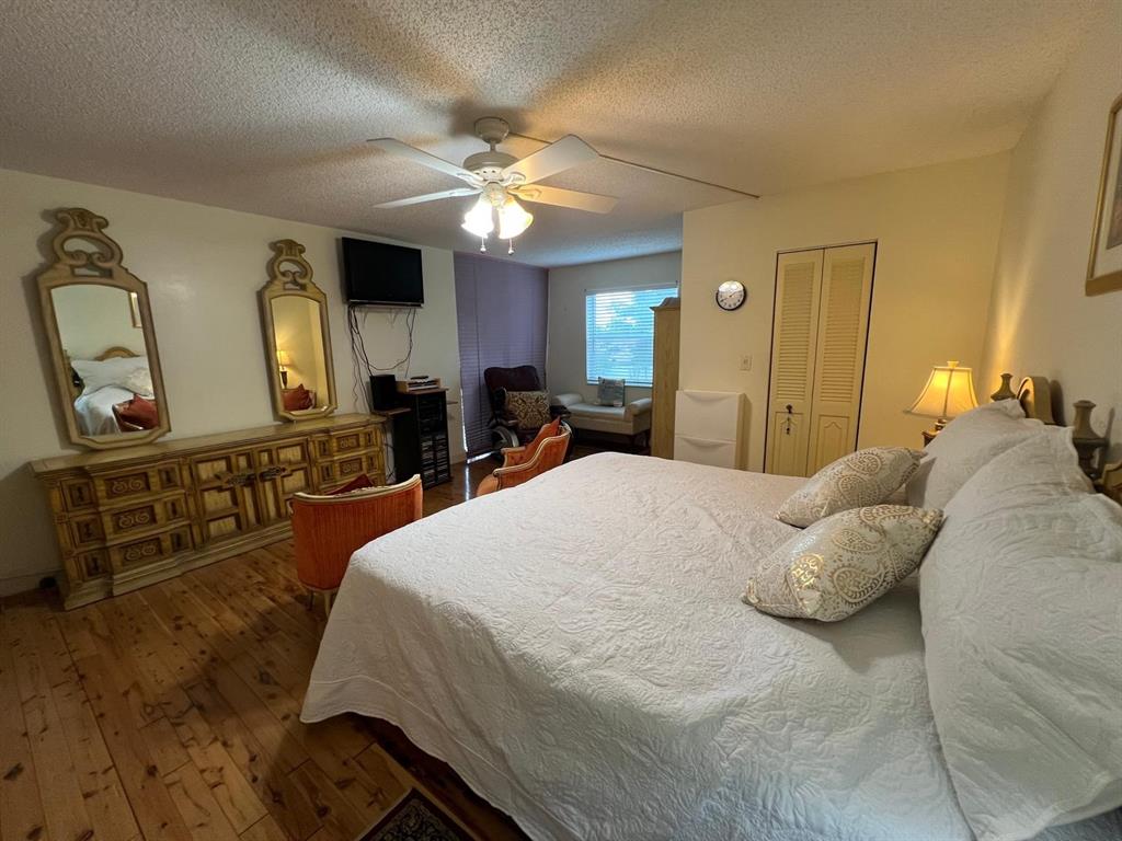 3910 Inverrary Boulevard, Unit 301B Lauderhill, FL 33319 - Photo 17 of 44 a bedroom with a bed a mirror on the dresser and a chandelier