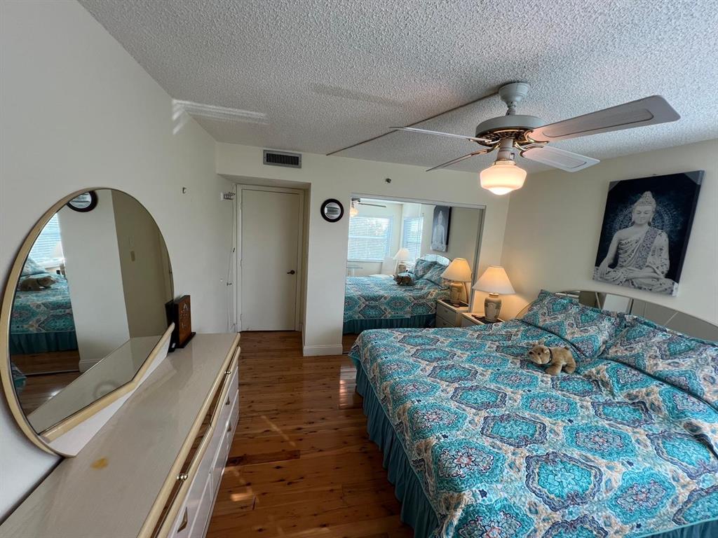 3910 Inverrary Boulevard, Unit 301B Lauderhill, FL 33319 - Photo 23 of 44 a bedroom with a bed a mirror on the dresser and a chandelier