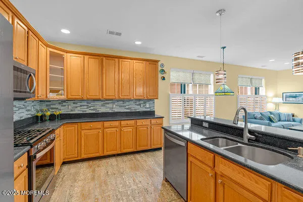 a kitchen with granite countertop a sink a counter space cabinets and stainless steel appliances