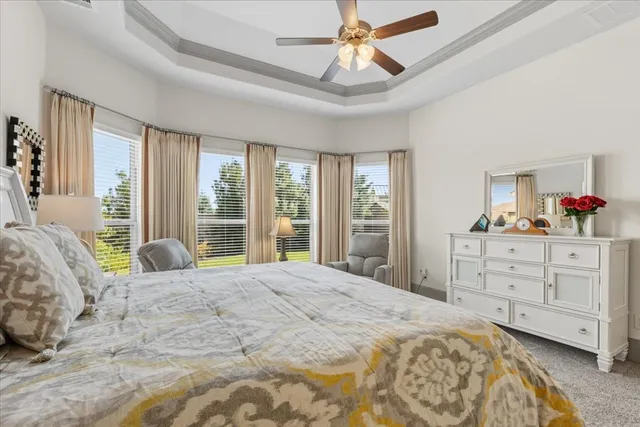 a bedroom with a large bed and a chandelier fan