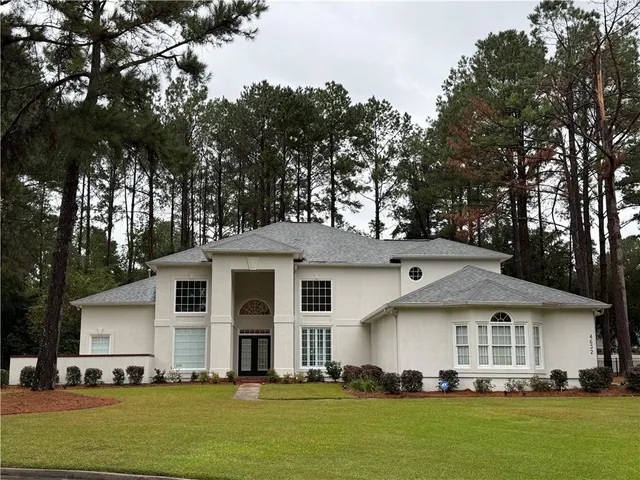 a view of house with outdoor space and trees in the background