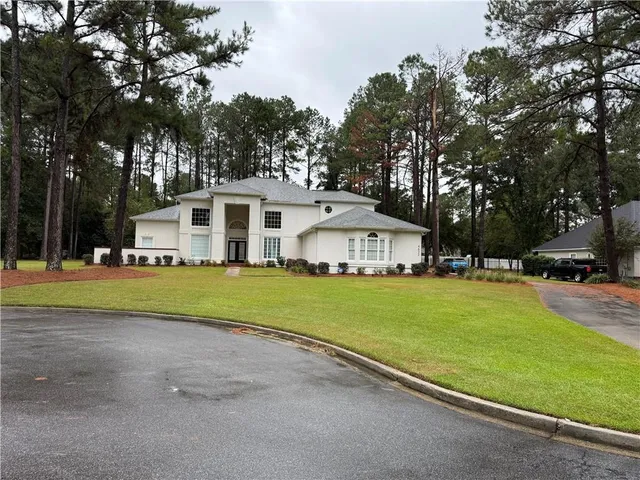 a view of a white house with a big yard and large trees