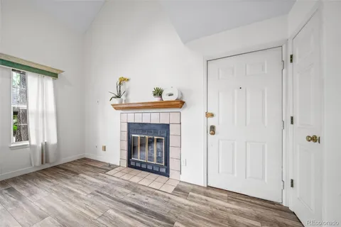a view of an empty room with wooden floor fireplace and a window