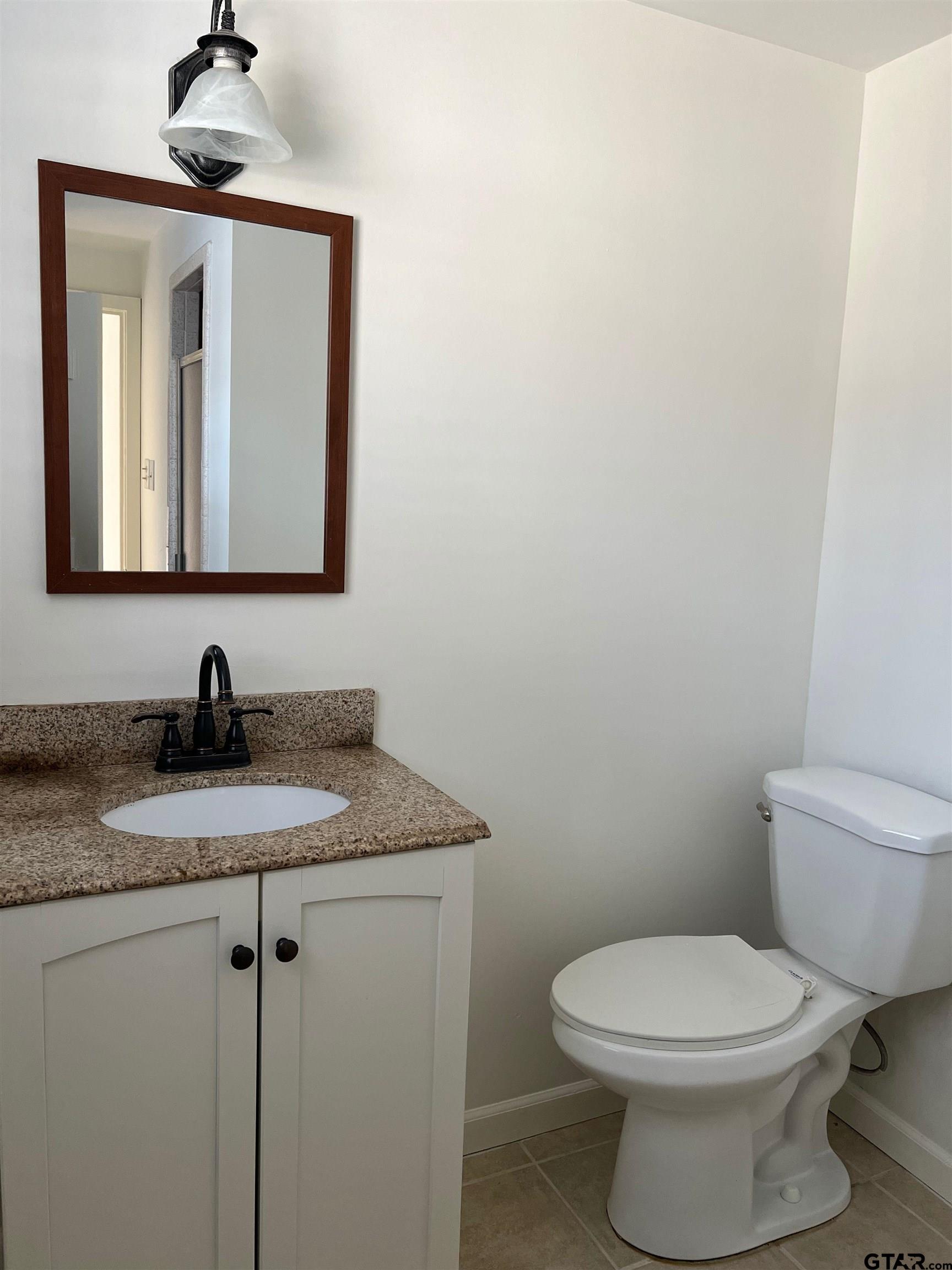 328 Mockingbird Lane Tyler, TX 75701 - Photo 12 of 12 a bathroom with a granite countertop toilet sink and mirror