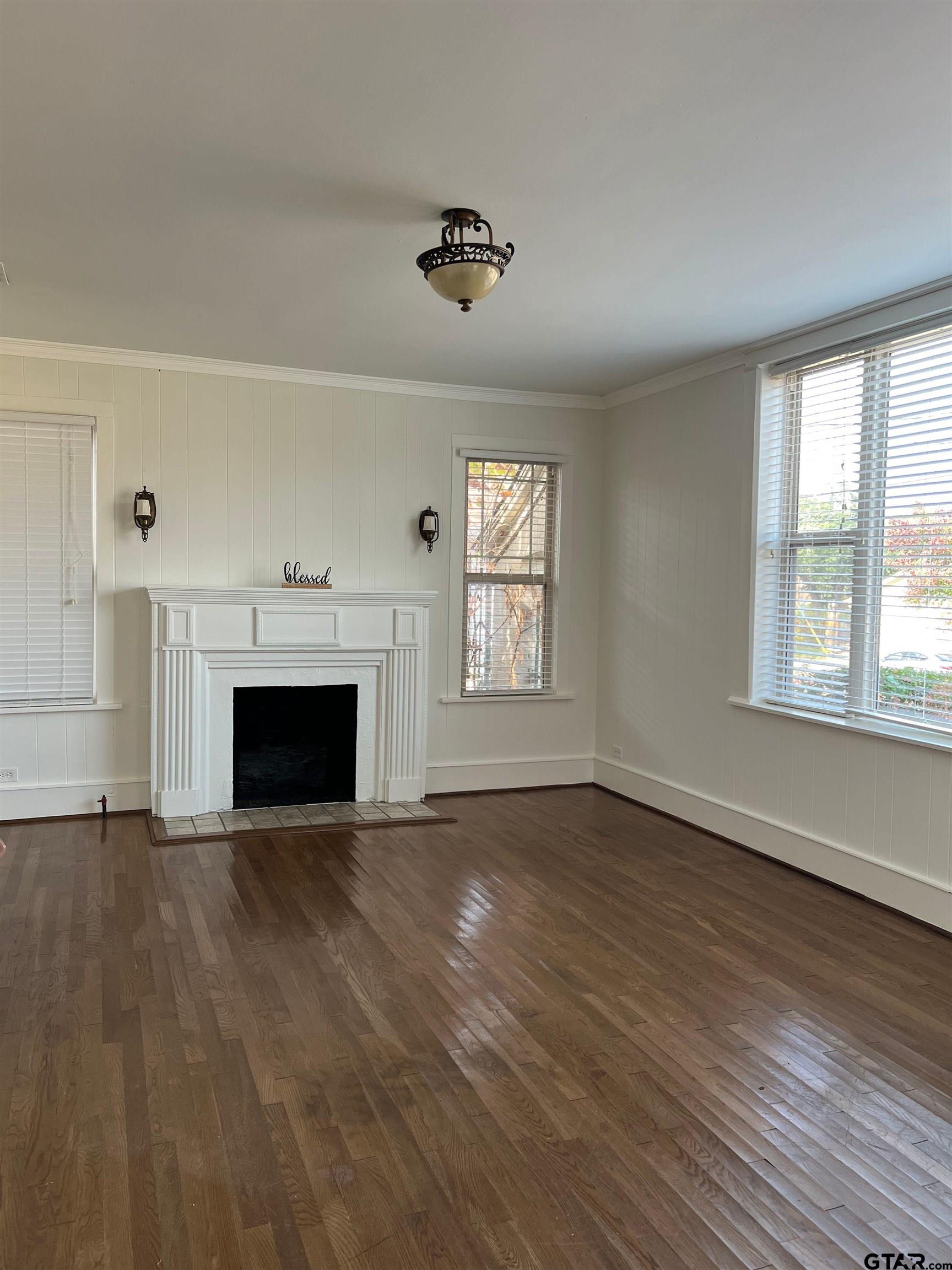 328 Mockingbird Lane Tyler, TX 75701 - Photo 3 of 12 an empty room with wooden floor fireplace and windows