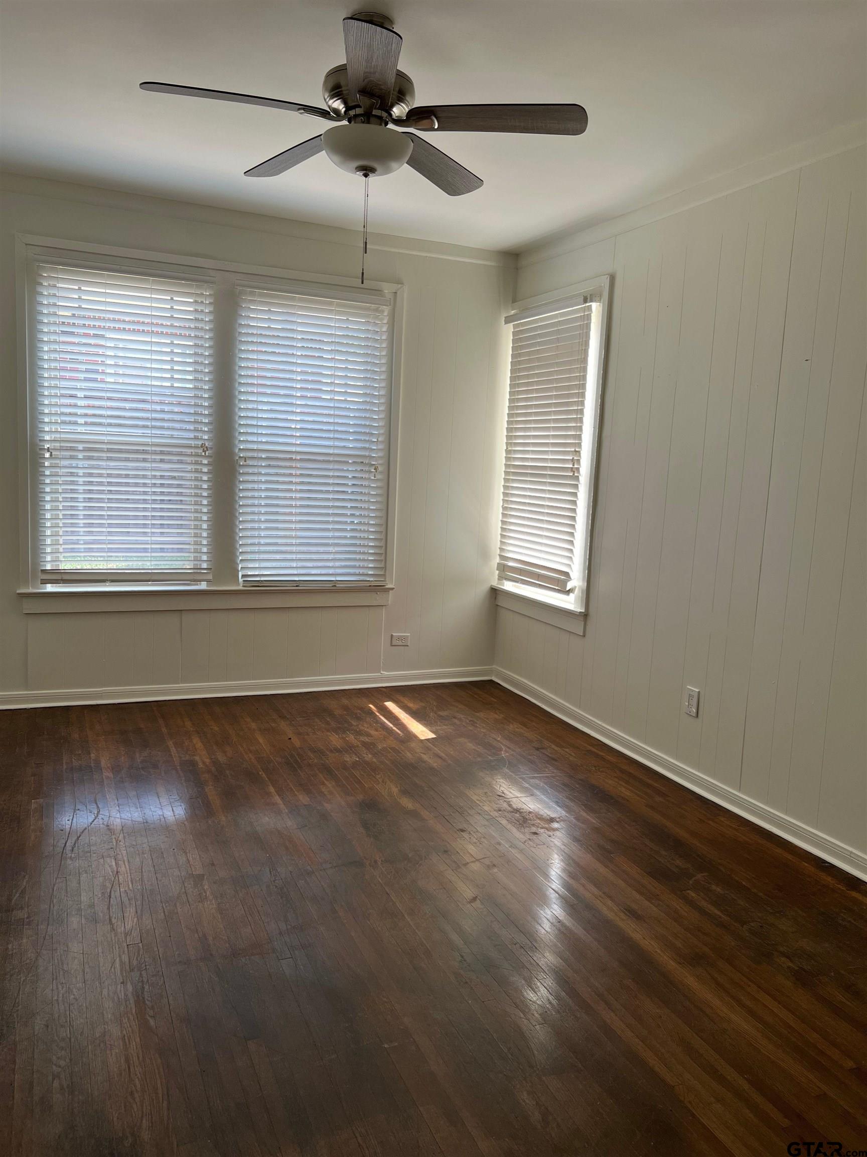 328 Mockingbird Lane Tyler, TX 75701 - Photo 7 of 12 an empty room with wooden floor chandelier fan and windows