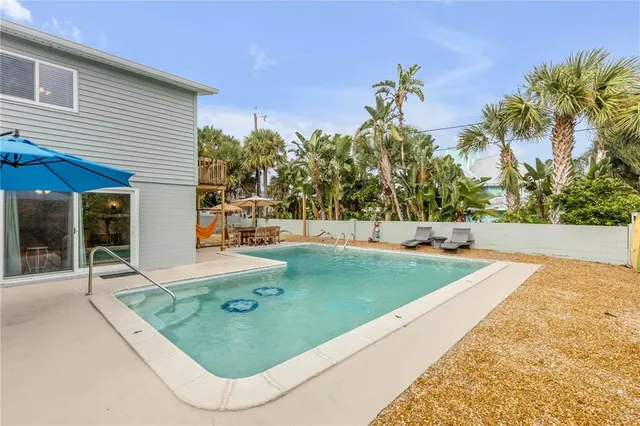 a backyard of a house with table and chairs under an umbrella