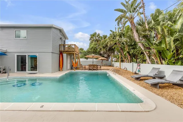a backyard of a house with table and chairs under an umbrella