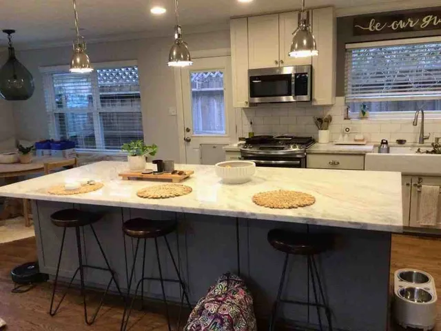 a kitchen with a sink a stove a kitchen island with chairs and cabinets