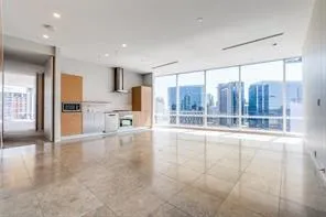a view of an empty room with a kitchen view and a window