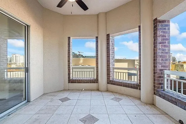 a view of an empty room with window and chandelier fan