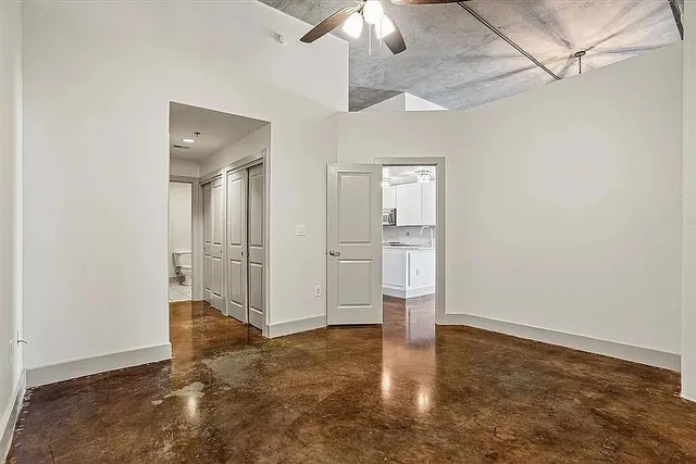 an empty room with chandelier fan and windows