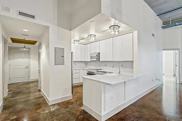 a kitchen with a sink a stove a refrigerator and white cabinets
