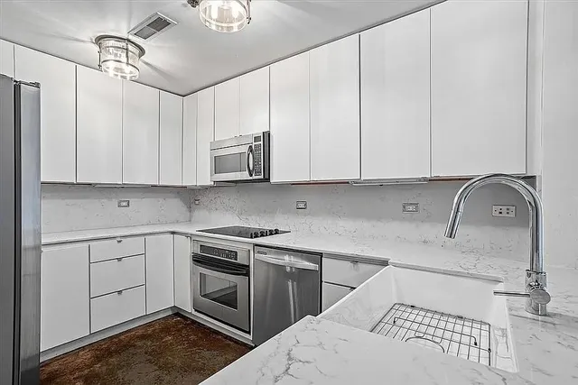 a kitchen with stainless steel appliances granite countertop a sink a stove and cabinets