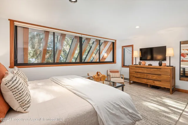 a bedroom with a bed and flat tv screen