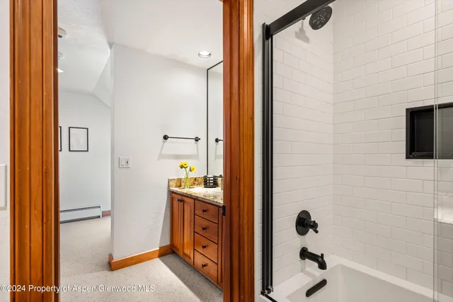 a bathroom with a granite countertop sink a mirror and shower