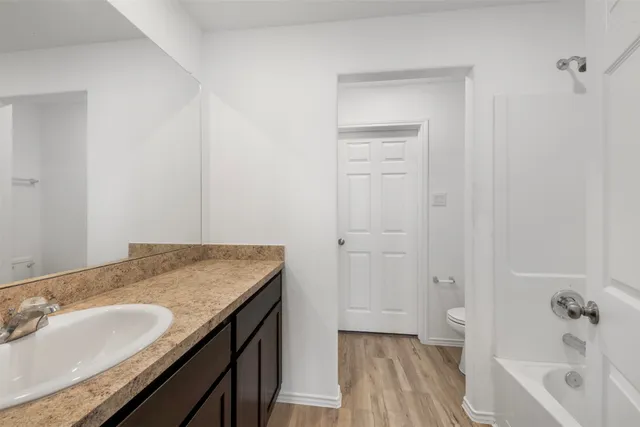 a bathroom with a granite countertop sink and a bathtub