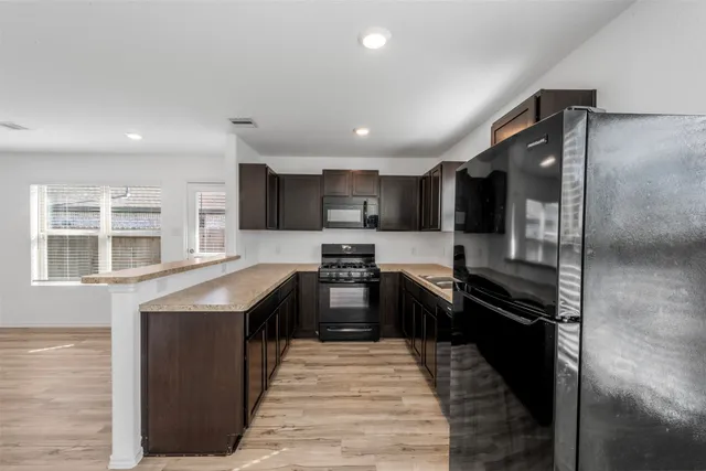 a kitchen with stainless steel appliances granite countertop refrigerator a sink and wooden cabinets