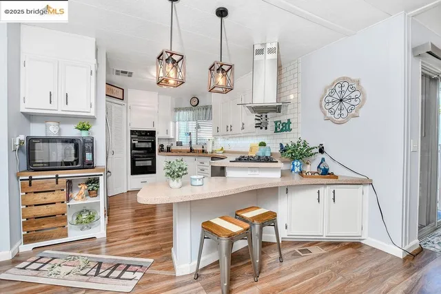 a kitchen with stainless steel appliances granite countertop a sink a stove and a wooden floors