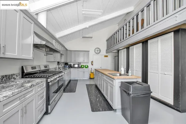 a kitchen with stainless steel appliances a sink a stove top oven a chimney and a refrigerator