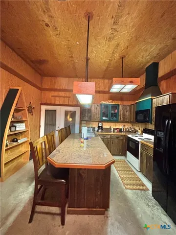 a kitchen with stainless steel appliances granite countertop a stove top oven a sink a dining table and chairs with wooden floor