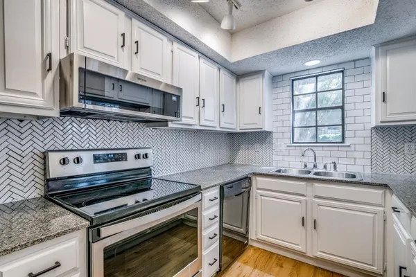 a kitchen with stainless steel appliances granite countertop a sink a stove a microwave and cabinets