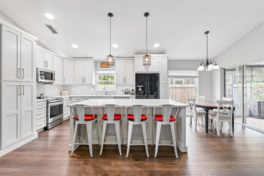325 Longshadows Court Ocoee, FL 34761 - Photo 12 of 34 a large kitchen with a table chairs stove and wooden floor