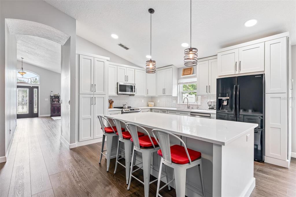 325 Longshadows Court Ocoee, FL 34761 - Photo 6 of 34 a large kitchen with stainless steel appliances kitchen island granite countertop a stove a refrigerator a oven a sink with a dining table and chairs