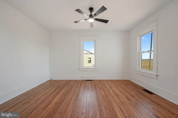 a view of empty room with wooden floor and fan