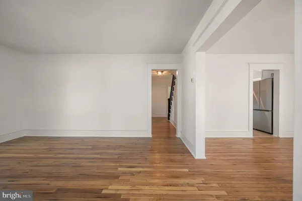 a view of an empty room with wooden floor and a kitchen