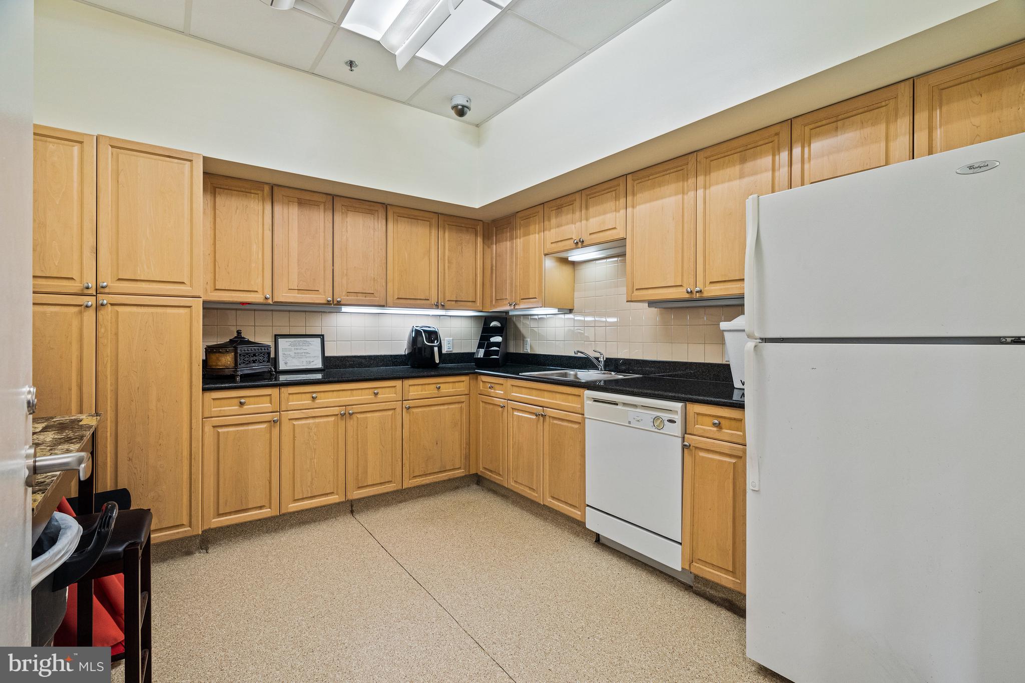 2726 Gallows Road, Unit 712 Vienna, VA 22180 - Photo 27 of 55 a kitchen with granite countertop a refrigerator a sink and white cabinets