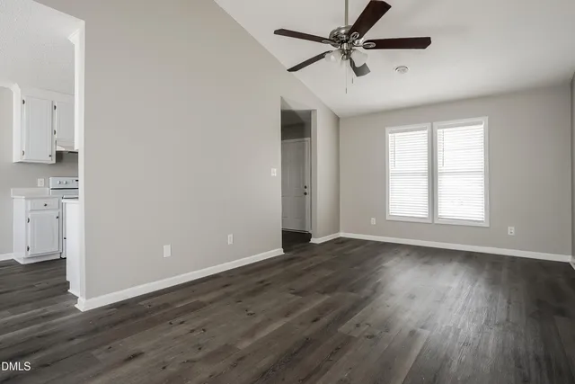 an empty room with wooden floor ceiling fan and windows