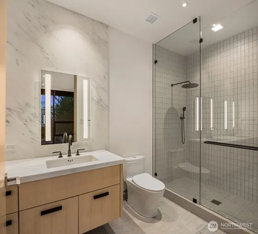 a bathroom with a shower sink mirror and toilet